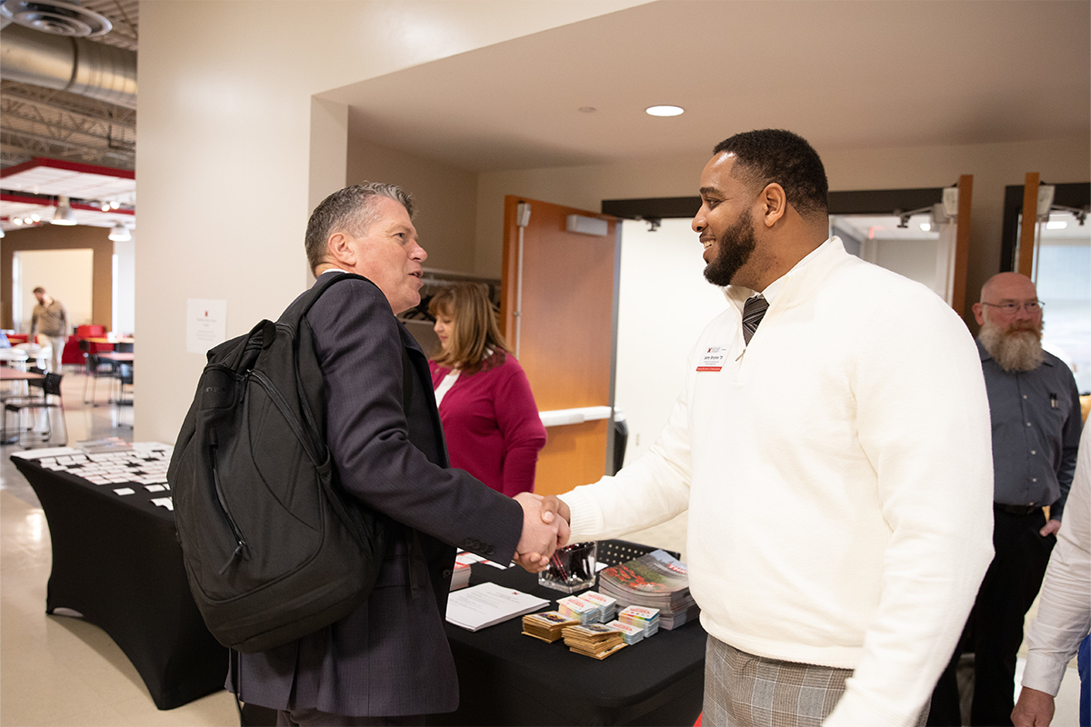 Miami Alumni meeting each other and shaking hands.